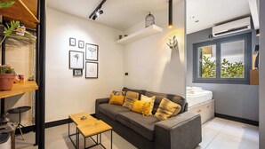 A modern living room with a grey sofa, wooden coffee table, and wall-mounted artwork. - Well Designed 1BR in Prime Kolonaki (Athina)