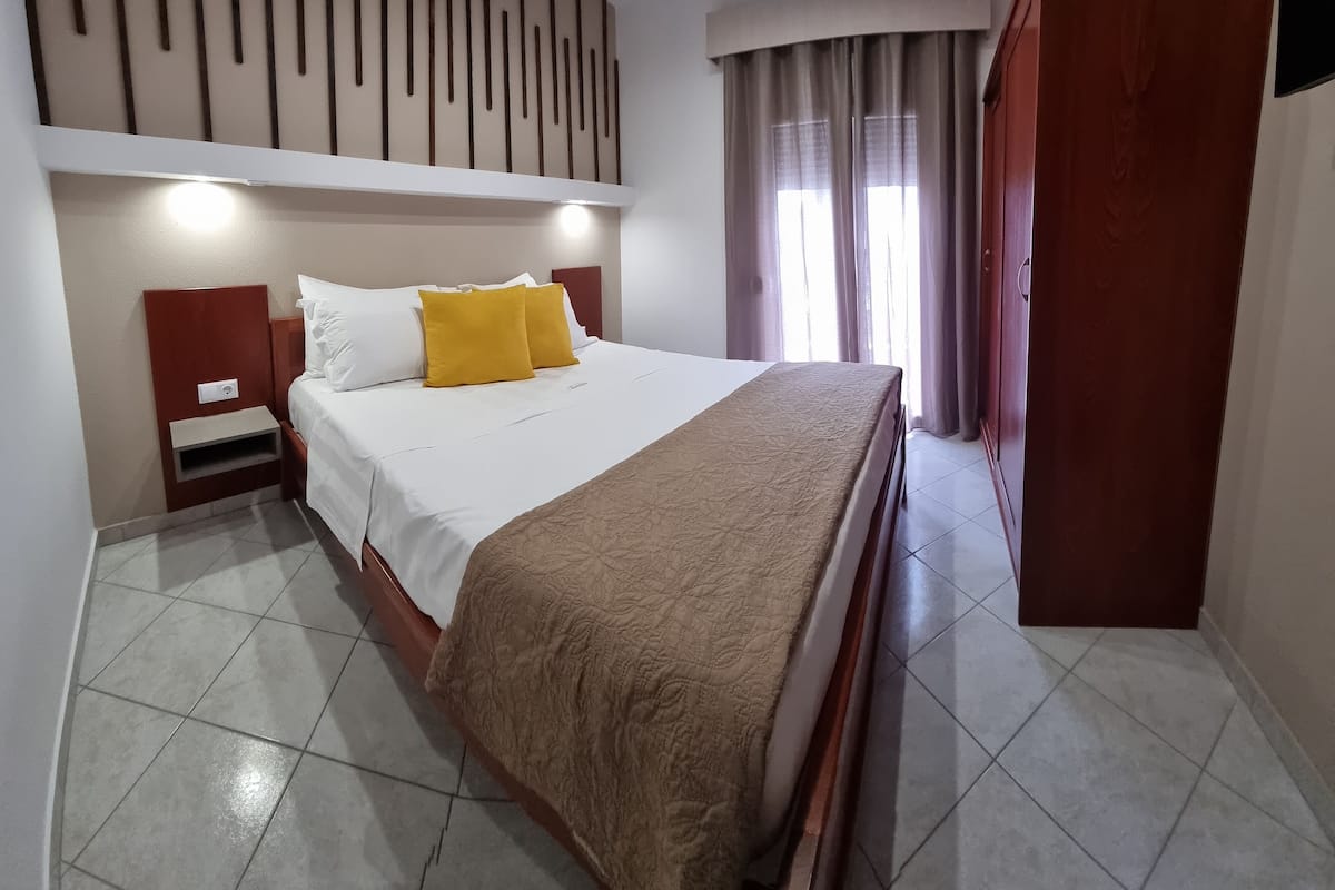 Een hotelkamer met een groot bed, een houten hoofdbord, een nachtkastje en een kledingkast.