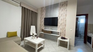 Un salon moderne comprenant un canapé, une table basse, un téléviseur fixé au mur (qui présente une texture particulière) et une petite table d’appoint.