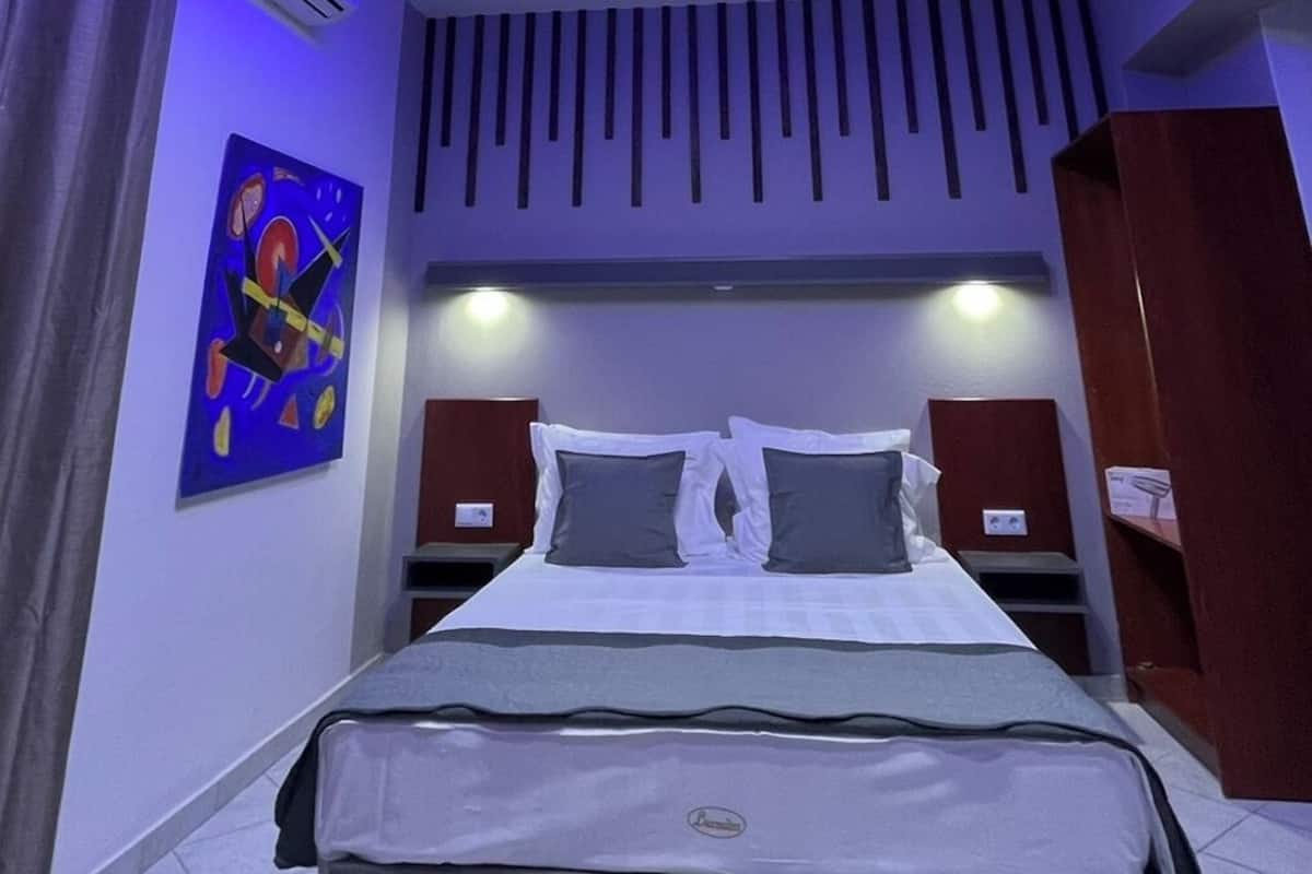 Een moderne slaapkamer met een bed, een plafondlamp en een schilderij aan de muur.