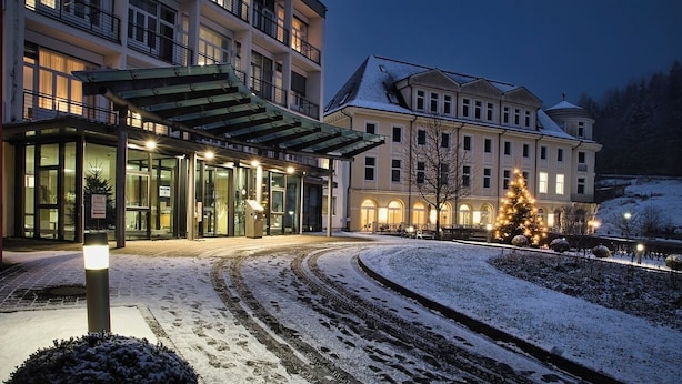 A hotel entrance with a covered walkway, snow-covered ground, and a Christmas tree. - Prime (Noida)