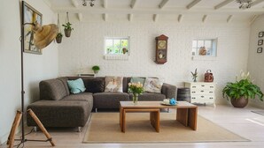 A cozy living room with a sectional sofa, a wooden coffee table, and a white brick wall. - Prime (Noida)