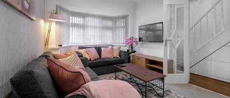 A modern living room with a grey sofa, a wooden coffee table, and a pink orchid.