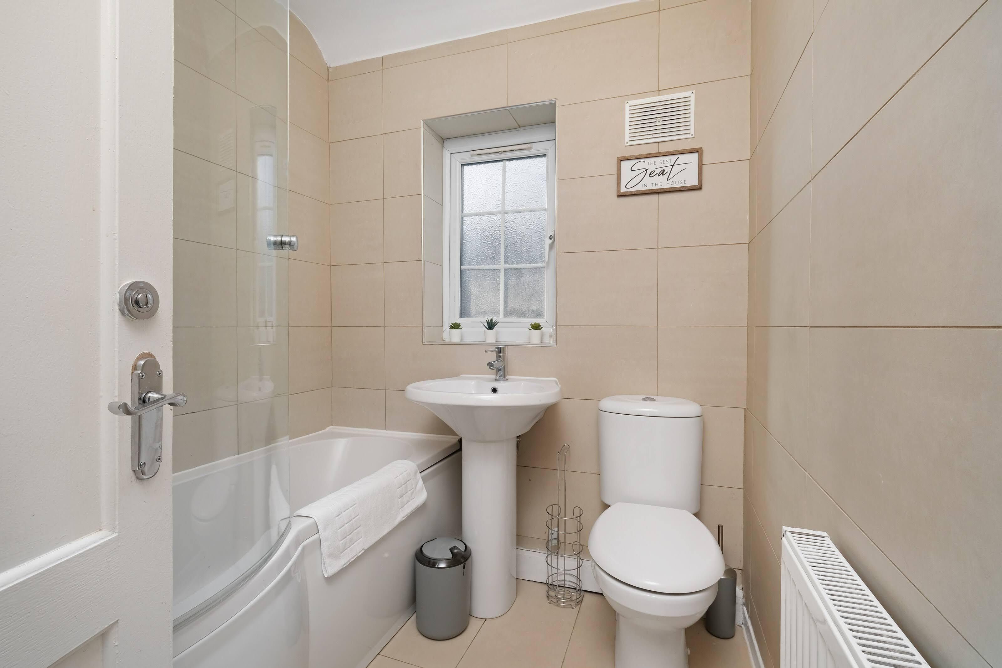 A bathroom with a bathtub, sink, toilet, and a window.