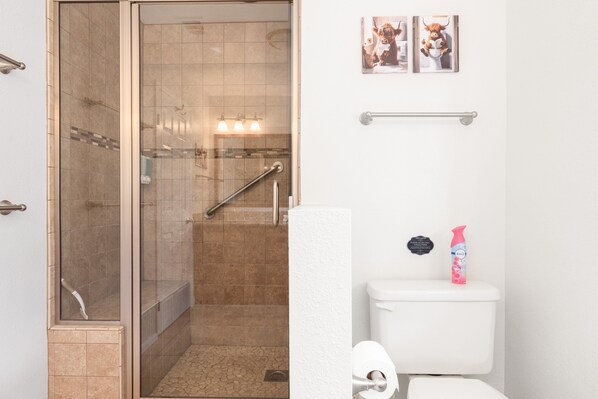 Un baño con ducha de vidrio, inodoro y toallero.