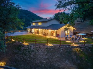 Una casa de dos pisos con un porche cubierto, un jacuzzi y un patio cercado.