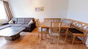 Una sala de estar con un sofá, una mesa de comedor de madera y sillas.