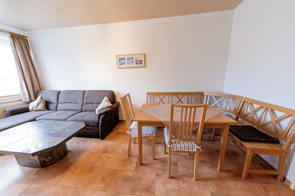 Ein Wohnzimmer mit einer Couch, einem Holzesstisch und Stühlen.