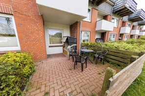 Eine gepflasterte Terrasse mit Sitzgelegenheiten, einer Holzbank und einem kleinen Tisch.