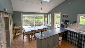 Een keuken met een dakraam, een houten eettafel en een inbouw kookeiland met spoelbak.