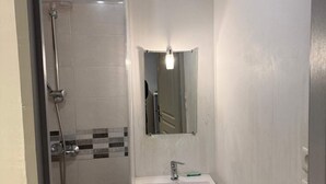 Un bagno piccolo con doccia, lavandino e specchio.