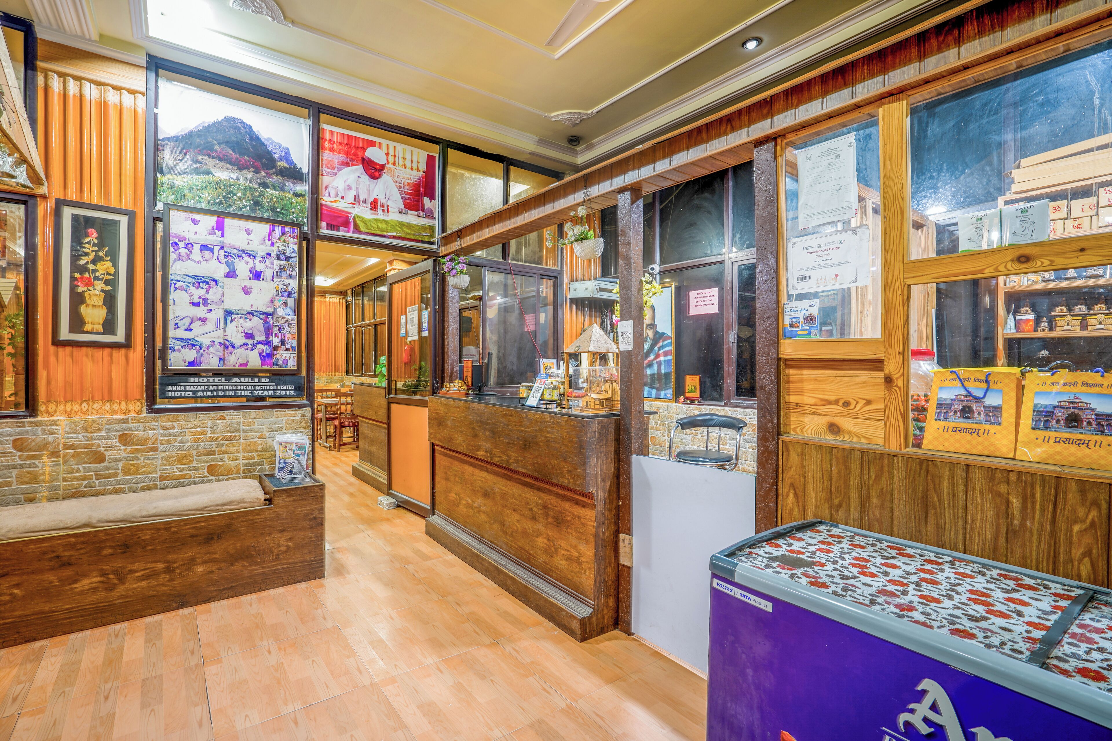 Uma área de recepção com balcão de madeira, um banco para acomodação e uma vitrine com lembranças.