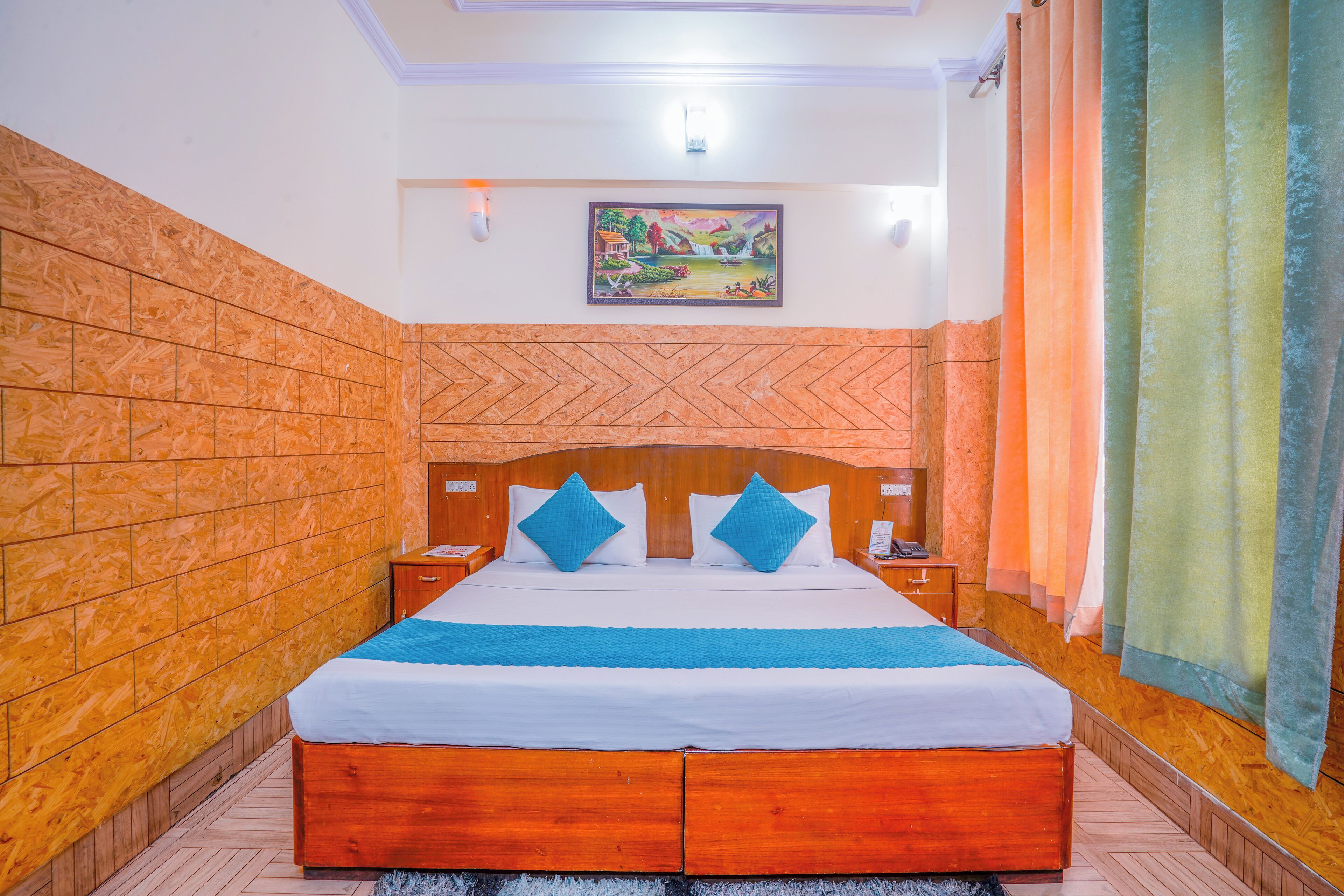 A neatly made bed with a blue and white bedspread, wooden headboard, and two blue pillows.