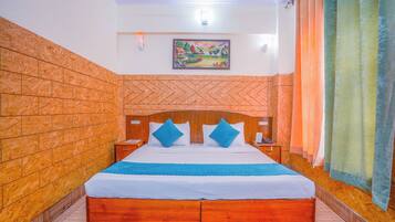 A neatly made bed with a blue and white bedspread, wooden headboard, and two blue pillows.