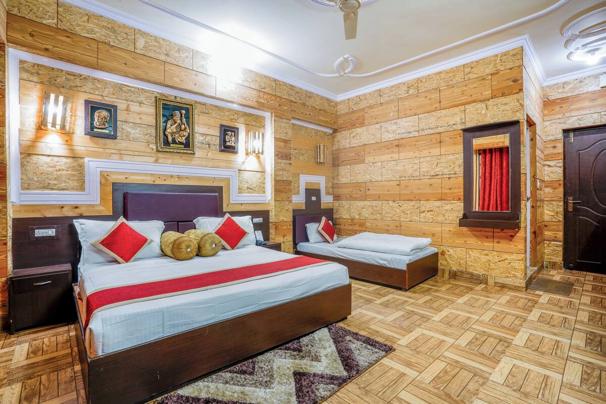 Une chambre avec deux lits, des murs en bois et un rideau rouge.