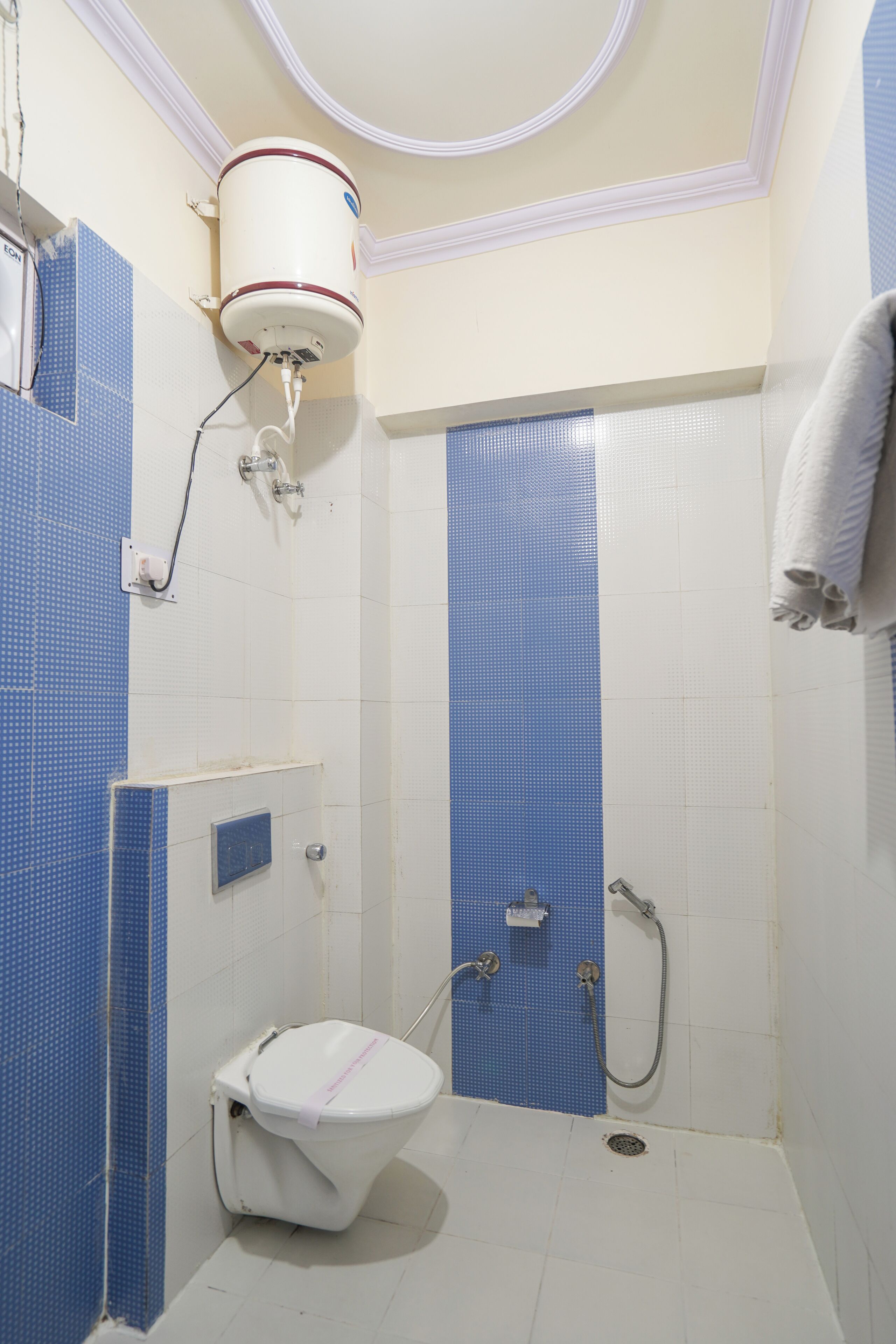 Un baño con inodoro, ducha y calentador de agua instalado en la pared.