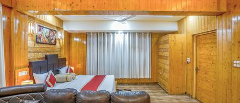 A wooden-paneled room with a bed, a leather sofa, and a ceiling fan.