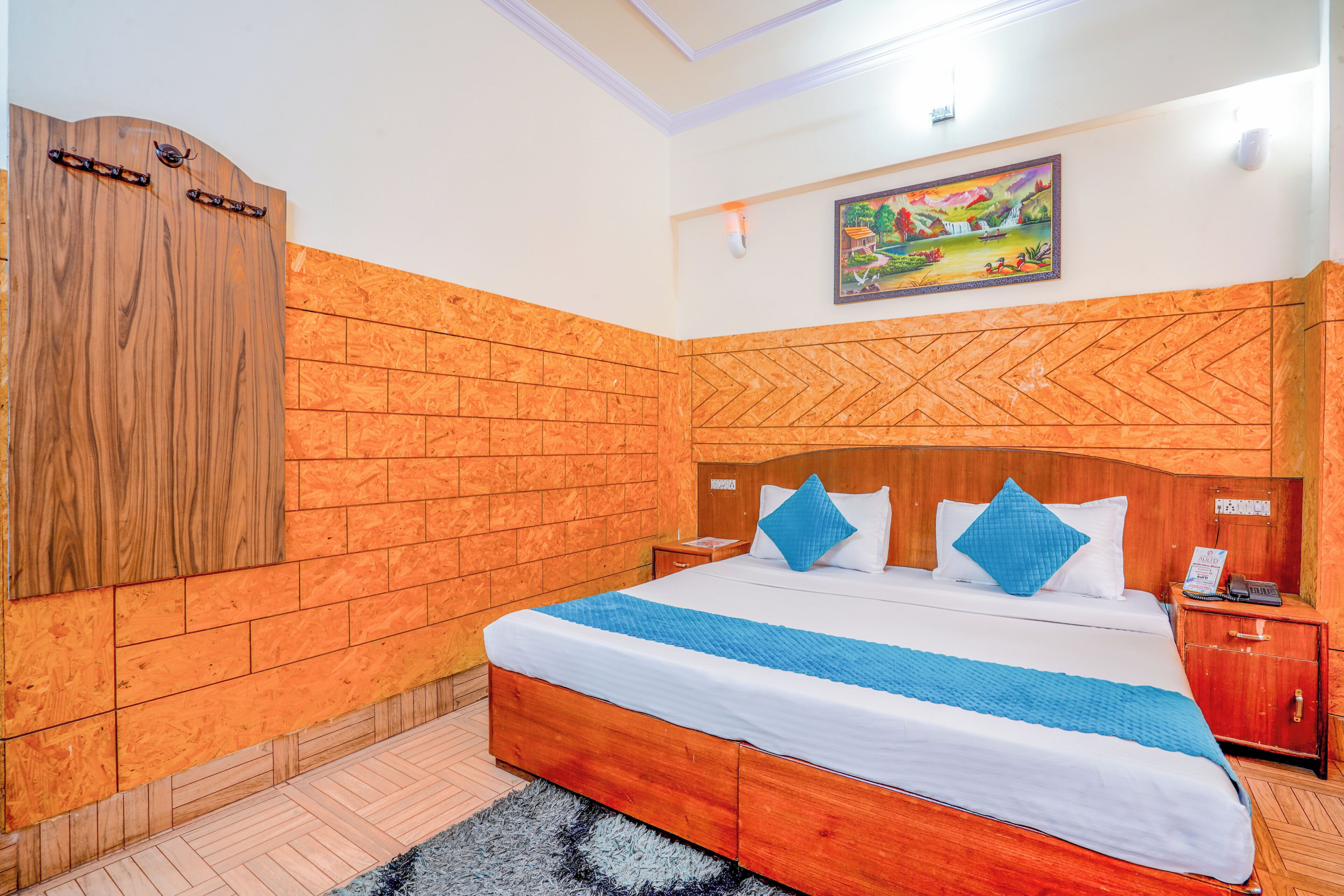 A bedroom with a wooden bed, a nightstand, a wardrobe, and a painting on the wall.