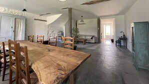 A spacious room with a wooden dining table, chairs, a sofa, and a small desk. - Fabrique des Luddites - chambres et gîte (Chatte)