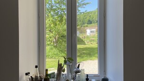 A kitchen with a large window, a sink, and various kitchen items on the windowsill. - Fabrique des Luddites - chambres et gîte (Chatte)