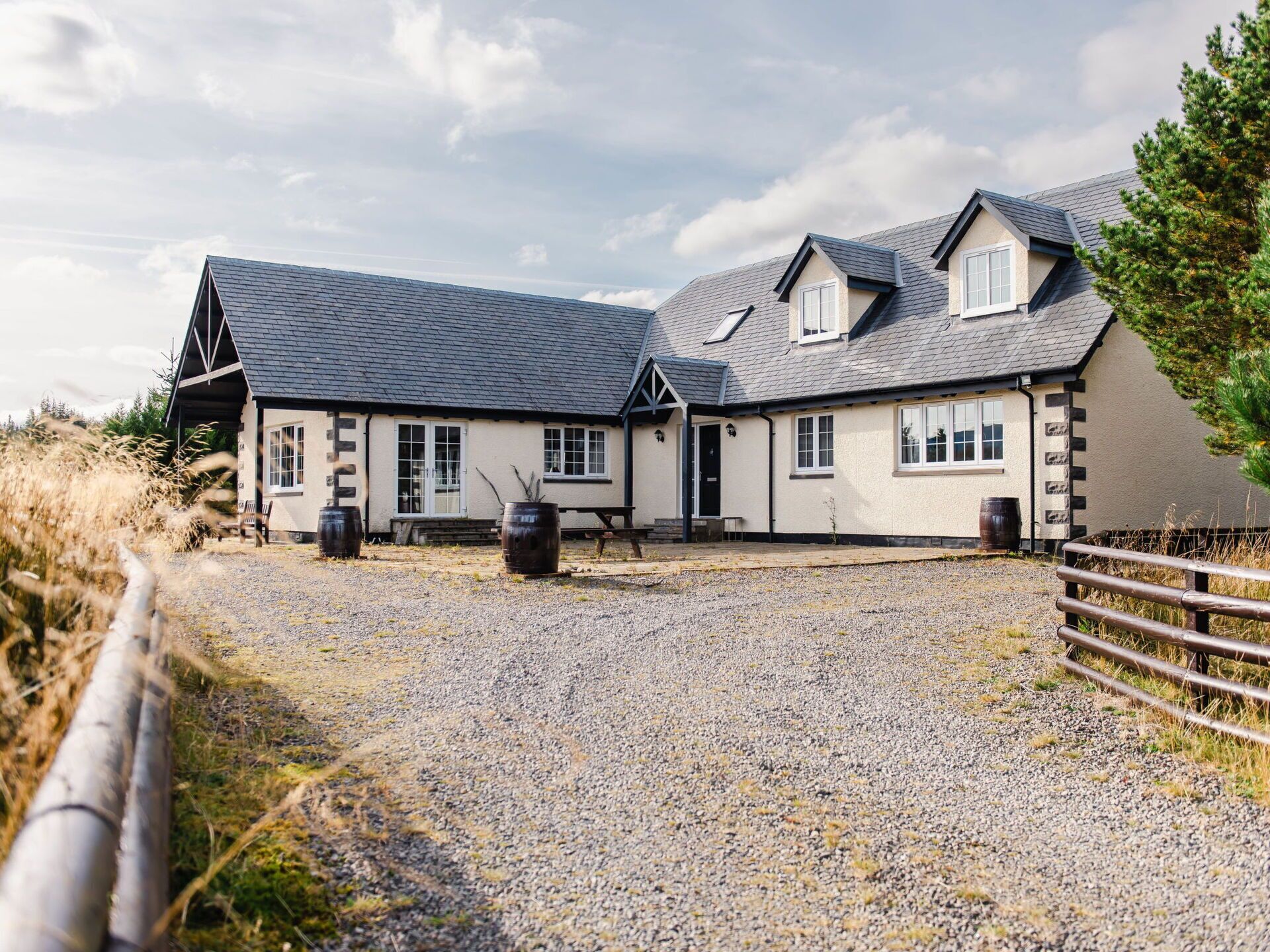 A two-story building with a gravel driveway and wooden fence.