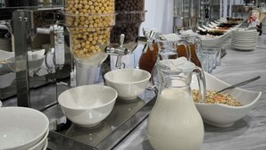 A buffet setup with various food dispensers and bowls. - Saroy Gardens Hotel (Fergana)