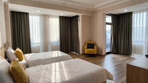 A hotel room with two beds, a desk, and a yellow armchair. - Saroy Gardens Hotel (Fergana)