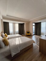 Habitación de hotel con dos camas, un escritorio y un sillón amarillo.