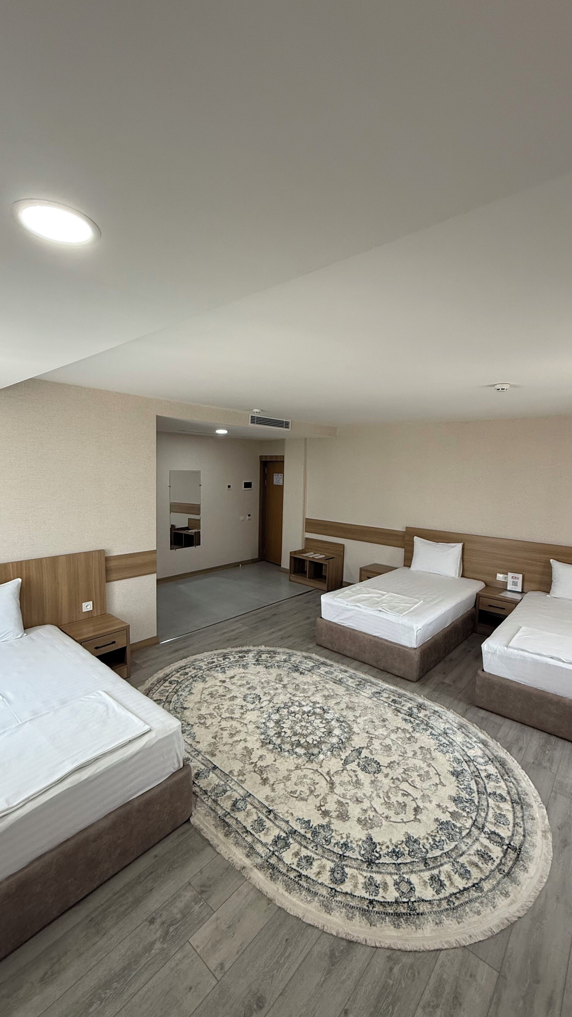 Une chambre d’hôtel avec deux lits, une grande moquette et une porte donnant sur une salle de bain.