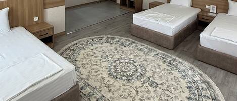 Una habitación de hotel con dos camas, una alfombra grande y una puerta que da al baño.