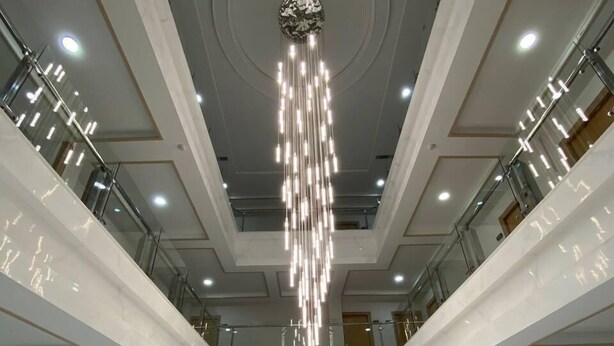 A multi-level atrium with a central chandelier, glass railings, and a symmetrical design. - Saroy Gardens Hotel (Fergana)