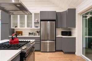 Eine moderne Küche mit einem Edelstahl-Kühlschrank, einer Mikrowelle und einem roten Wasserkocher auf dem Herd.