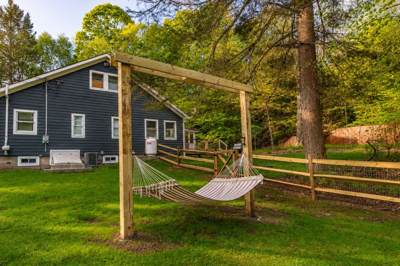 A house with a wooden swing set in a grassy yard.