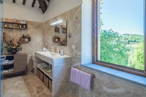 Ein Badezimmer mit großem Fenster, Waschbecken und Spiegel.