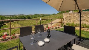 An outdoor dining area with a table, chairs, and an umbrella. - Villetta Cafaggio Ac Panzano In Chianti (Castellina in Chianti)