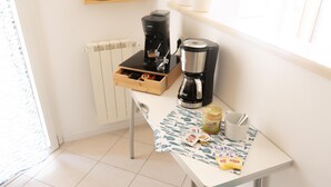 Eine kleine Küchenzeile mit Kaffeemaschine, Erdnussbutter und einer Tasse auf einem Tisch.