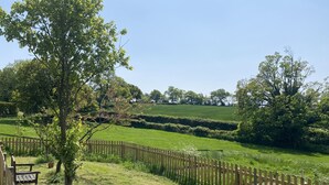 Un paysage rural avec une clôture en bois, des champs couverts d’herbe et des arbres.