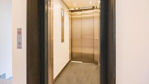 Un ascensor amb interior metàl·lic i sòl amb moqueta.