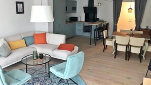 Un saló modern amb un sofà, cadires, una taula de centre i una zona de menjador amb taula i cadires.