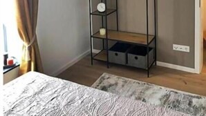Un dormitori amb llit, llum penjant, armari i una petita estanteria.