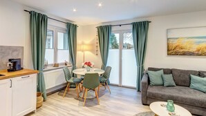 A modern living room with a dining area, a sofa, and a coffee machine. - Haus Barnheide, Whg. Silbermöwe in Bansin - your retreat with balcony (Bansin)