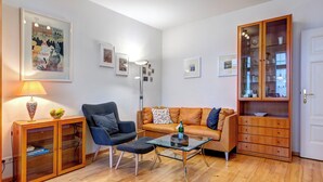 Una sala de estar con sofá, sillón, mesa de centro y aparador con puertas de vidrio.