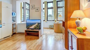 Una sala de estar moderna con una televisión de pantalla plana, piso de madera, un comedor con una lámpara y un frutero.