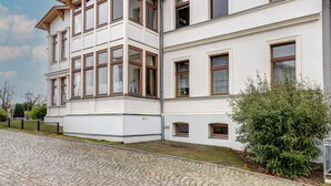 Un edificio de varios pisos con un camino de adoquines y un pequeño jardín.