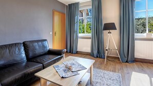 Ett modernt vardagsrum med en svart lädersoffa, ett soffbord i trä och en golvlampa.