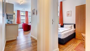 Habitación de hotel con una cama, un armario de madera, un escritorio con una silla y un sillón rojo.