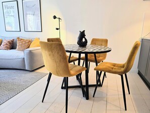 Un salon moderne avec une table ronde, quatre chaises, un canapé et deux tableaux encadrés accrochés au mur.
