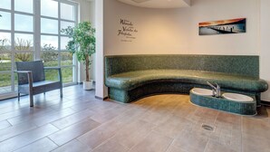 Un salon moderne avec un canapé vert aux lignes courbes, une petite table ronde et une plante en pot.