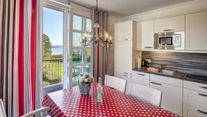 A modern kitchen with white cabinets, a stainless steel microwave, and a dining area with a red and white polka dot tablecloth. - Residenz am Balmer See, apartment 13 in Balm - fantastic lake view & pure relaxation (Balm)