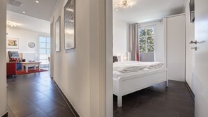 A modern bedroom with a large bed, a wardrobe, and a window with curtains. - Residenz am Balmer See, apartment 13 in Balm - fantastic lake view & pure relaxation (Balm)